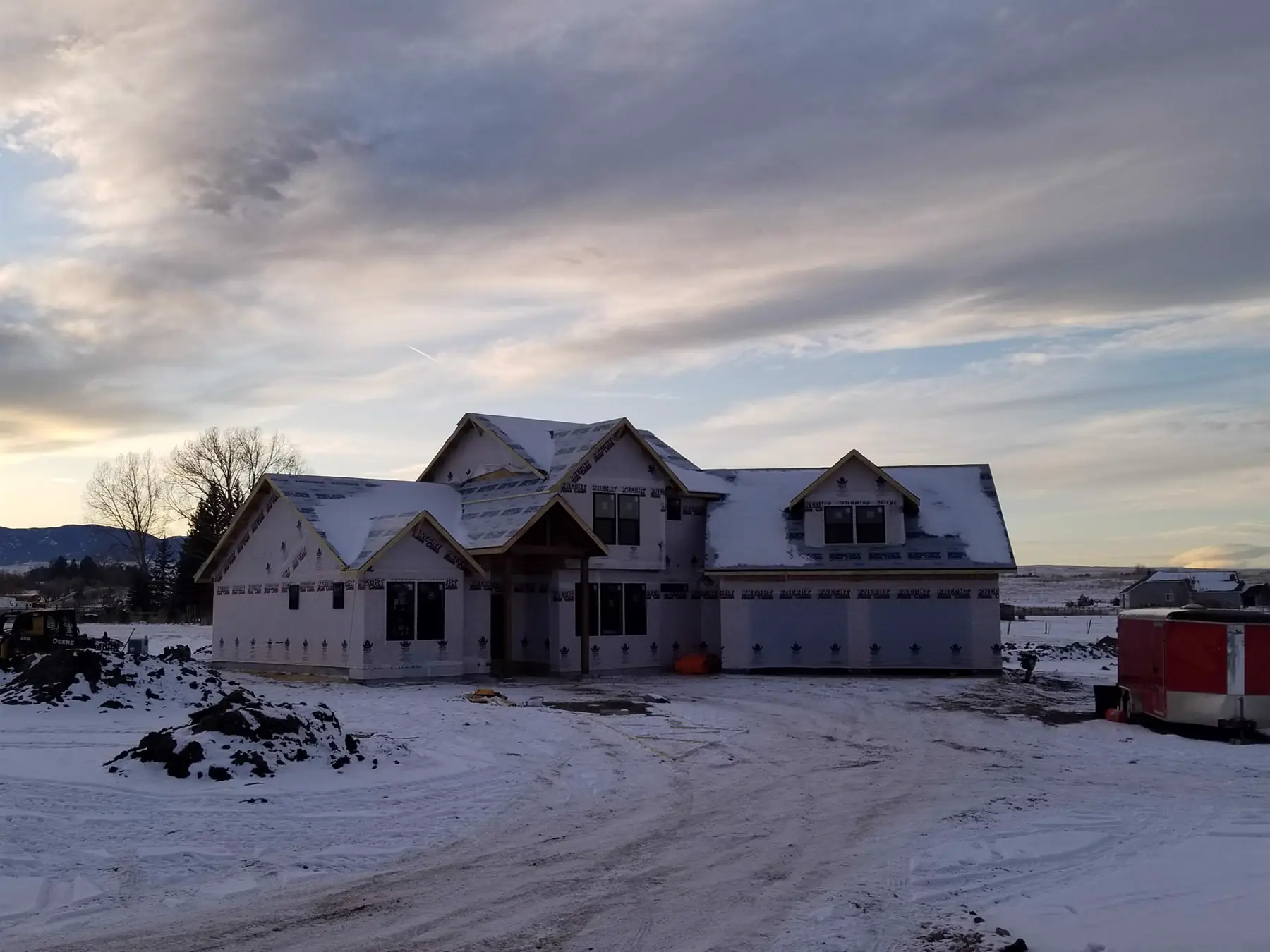 A two-story custom home dried in for winter at dusk