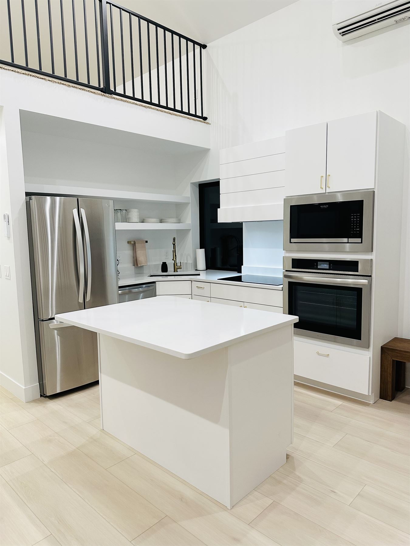 White kitchen beneath an open loft, built by Build It Brothers