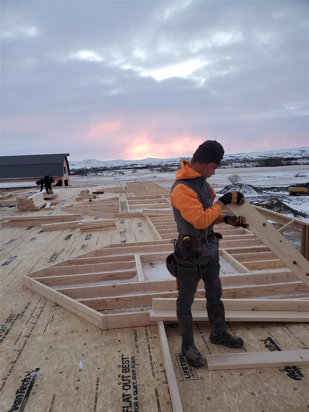 A Build It Brothers builder framing at sunrise